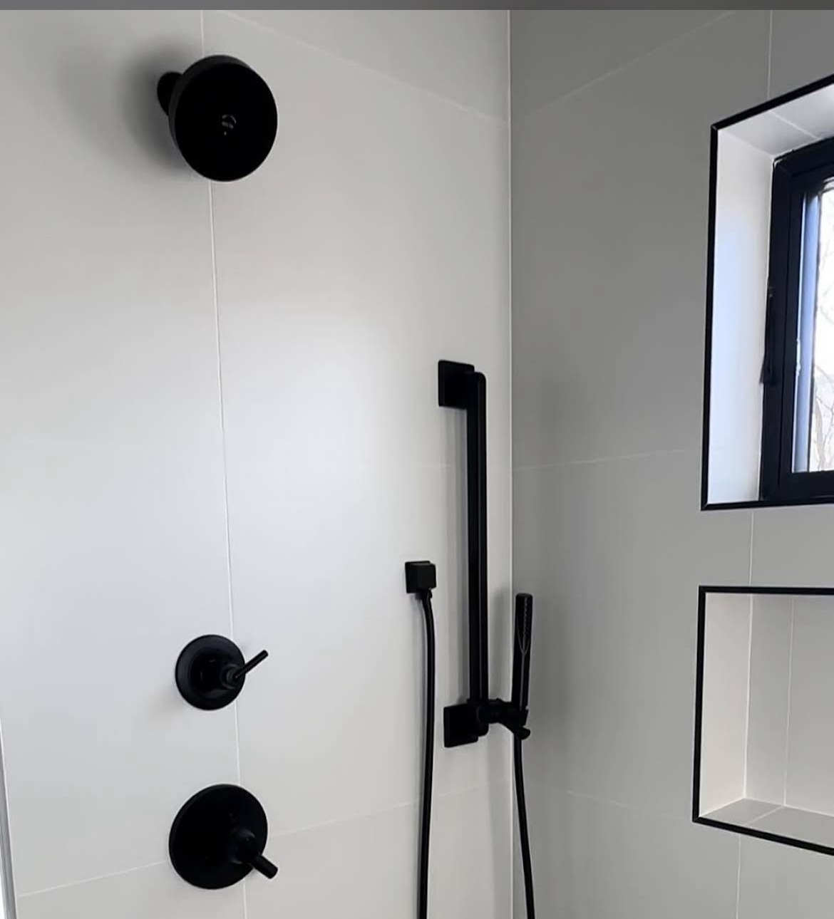 Tiled shower with matte black rainfall and handheld fixtures